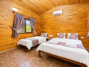 two beds in a room with wooden walls at Izgen Bungalows in Cıralı