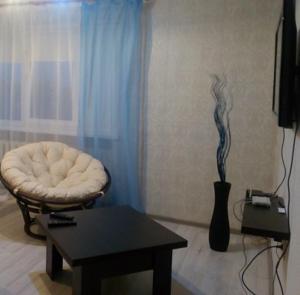 a living room with a chair and a table at Apartment on Chapaeva in Borisov