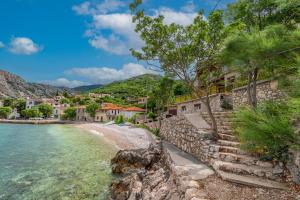 a stone wall next to a beach with houses at Apartments Steps from the Sea in Donja Klada