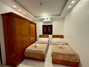 a room with two beds in a room with a cabinet at private studio - djorff area in Al Aqālitah