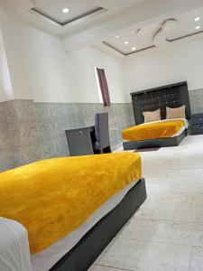two beds in a room with yellow blankets at London 248 in Mexico City