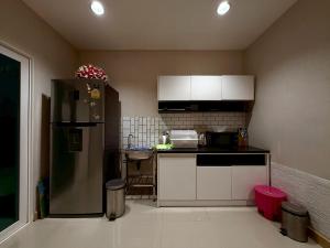 a kitchen with a stainless steel refrigerator and white cabinets at The Modern Nest in Ban Bang Chan