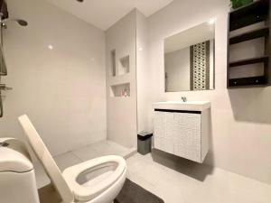 a white bathroom with a toilet and a sink at The Modern Nest in Ban Bang Chan