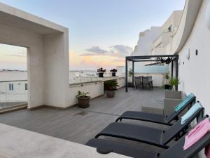 a balcony with chairs and tables on a building at Eva's Penthouse with private Swimming pool by ELDI in Il-Gżira