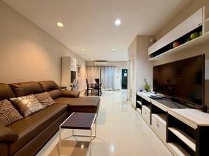 a living room with a brown couch and a television at The Modern Nest in Ban Bang Chan