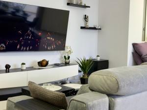 a living room with a couch and a tv on the wall at Eva's Penthouse with private Swimming pool by ELDI in Il-Gżira