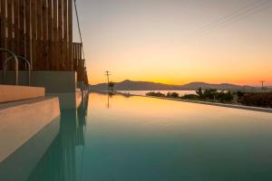 a swimming pool with the sunset in the background at Sunset View Paleros - Boutique Suites in Paleros