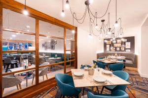 a restaurant with tables and chairs and a chandelier at Holiday Inn Stevenage by IHG in Stevenage