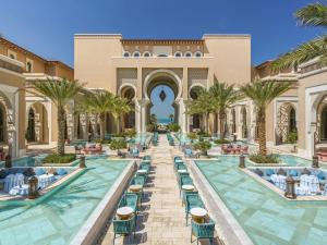 an exterior view of a resort with chairs and palm trees at Rixos Premium Saadiyat Island - All Inclusive in Abu Dhabi