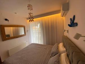 a bedroom with a bed and a mirror and a window at Irini Seaside Apartment in Paleo Tsifliki