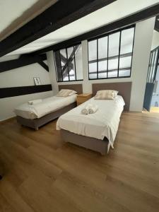 two beds in a room with wood floors and windows at Jolie maison de village à Grimaud in Grimaud