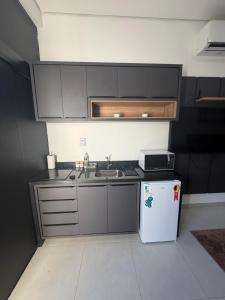 a small kitchen with a sink and a refrigerator at Loft bem localizado na cidade! in Boa Vista