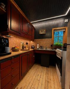 a kitchen with wooden cabinets and a wooden floor at Forest Cabin by the Water in Ålesund +21 photos