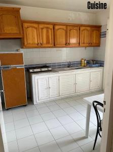 a kitchen with wooden cabinets and a white tiled floor at Appartement S3 in Mahdia in Mahdia +10 photos