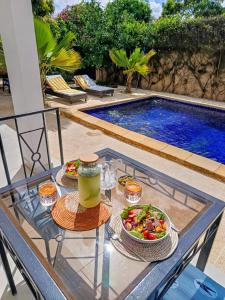 a glass table with a salad and a drink on it at Villa DOUDOU in Somone