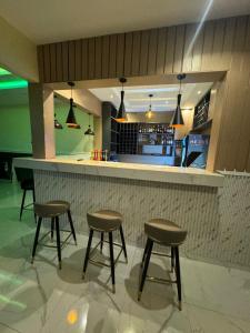 a bar with three stools in front of a counter at Leebwill Hotel & Apartment in Eku