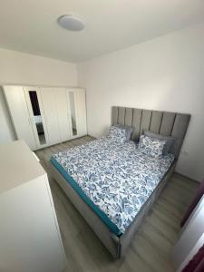 a bedroom with a bed with blue and white sheets and pillows at C&A Apartment in Giroc +6 photos