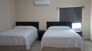 two beds in a hotel room with white sheets at Hotel palma de oro in Puerto Peñasco +15 photos