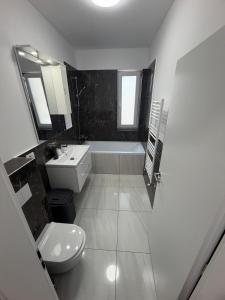 a bathroom with a sink and a toilet and a tub at C&A Apartment in Giroc