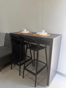 a black table with two chairs and two cups on top at Loft bem localizado na cidade! in Boa Vista