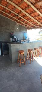 a kitchen with four wooden stools and a counter at Suíte Adam 2 em Caraíva com Piscina 900m da Vila in Caraíva