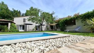 a swimming pool with rocks next to a house at Ginette et Marcel la maison in Saint-Rémy-de-Provence