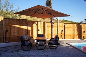 a patio with two chairs and an umbrella next to a pool at Lakeside Palms in Tirana