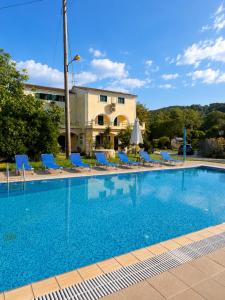 a swimming pool with blue chairs and a building at Pangea Corfu Villa in Sidari