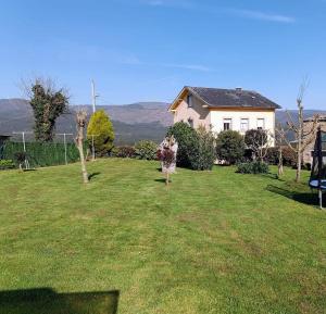 a woman walking in the yard of a house at Apartamento Duplex con jardín A Casiña de Divina in Lago