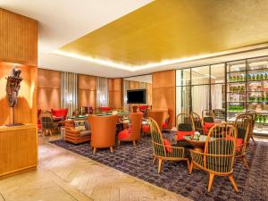 eine Hotellobby mit Tischen und Stühlen und einem Fernseher in der Unterkunft Movenpick Hotel Abidjan in Abidjan