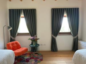 a bedroom with two windows with green curtains and a chair at Il Rustico di Corte Palù in San Martino Buon Albergo +21 photos