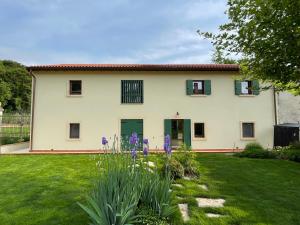 a large white house with green windows and purple flowers at Il Rustico di Corte Palù in San Martino Buon Albergo