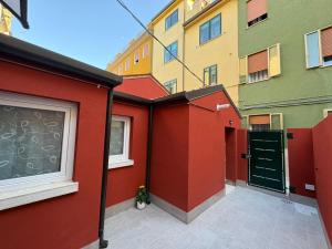 a building with a red wall and a green door at Casa Gina in Chioggia