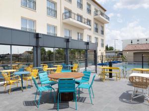 a patio with tables and chairs in front of a building at Ibis Styles Miramas in Miramas