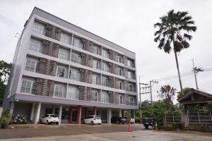 a large building with cars parked in a parking lot at Chompu Nakarin Apartment in Trang