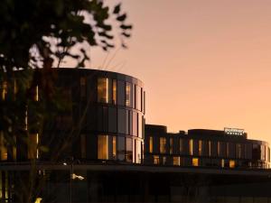 a tall glass building with a sunset in the background at Pullman Sydney Penrith in Penrith
