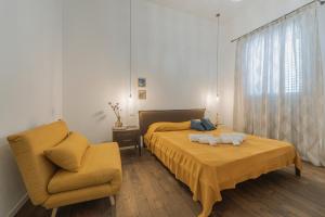 a bedroom with a yellow bed and a chair at Casa Ritunno Rooms in Favignana