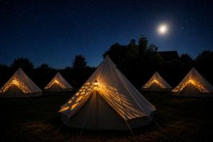 a group of tents in a field at night at The Ozorian Rooms & Glamping in Ozora