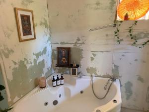 a bathroom with a bath tub with a painting at The Ozorian Rooms & Glamping in Ozora +30 photos