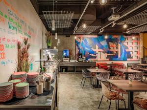 a restaurant with tables and chairs and a mural at ibis Styles Ljubljana The Fuzzy Log in Ljubljana
