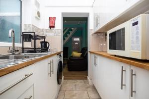 a kitchen with a sink and a microwave at 2Bd Mid Terrace Close To Station in Stoke on Trent