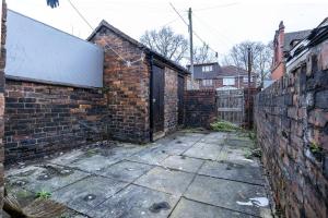 an alley with a brick wall and a door at 2Bd Mid Terrace Close To Station in Stoke on Trent
