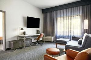 a hotel room with a desk and a living room at Courtyard Memphis Germantown in Memphis