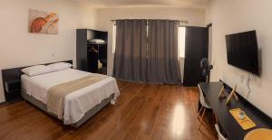 a bedroom with a bed and a desk and a television at Nosso Hotel Extrema - recém inaugurado in Extrema