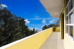 a balcony with a yellow wall and a blue sky at Hotel O Ghoom Formerly Aps Homestay in Darjeeling +34 photos