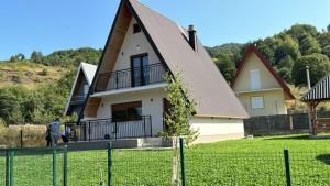 a house with a gambrel roof and a man standing in front of it at Veruša - Maksim's house in Veruša