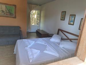 a bedroom with a bed with white sheets and a couch at Pousada Encanto dos Olhos in Alexânia