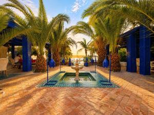 a fountain in the middle of a courtyard with palm trees at Rive Du Lac in Lalla Takerkoust