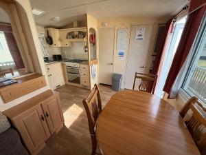 a kitchen and dining room with a table in a caravan at Bell Bank C8 - pet friendly, bed linen, close to bars and shops - Meadow Lakes Caravan & Lodge Hire in Chapel Saint Leonards