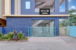 a building with a blue wall and a gate at OYO Hotel O Amaravathi Road Annapurna Nagar in Guntūr
